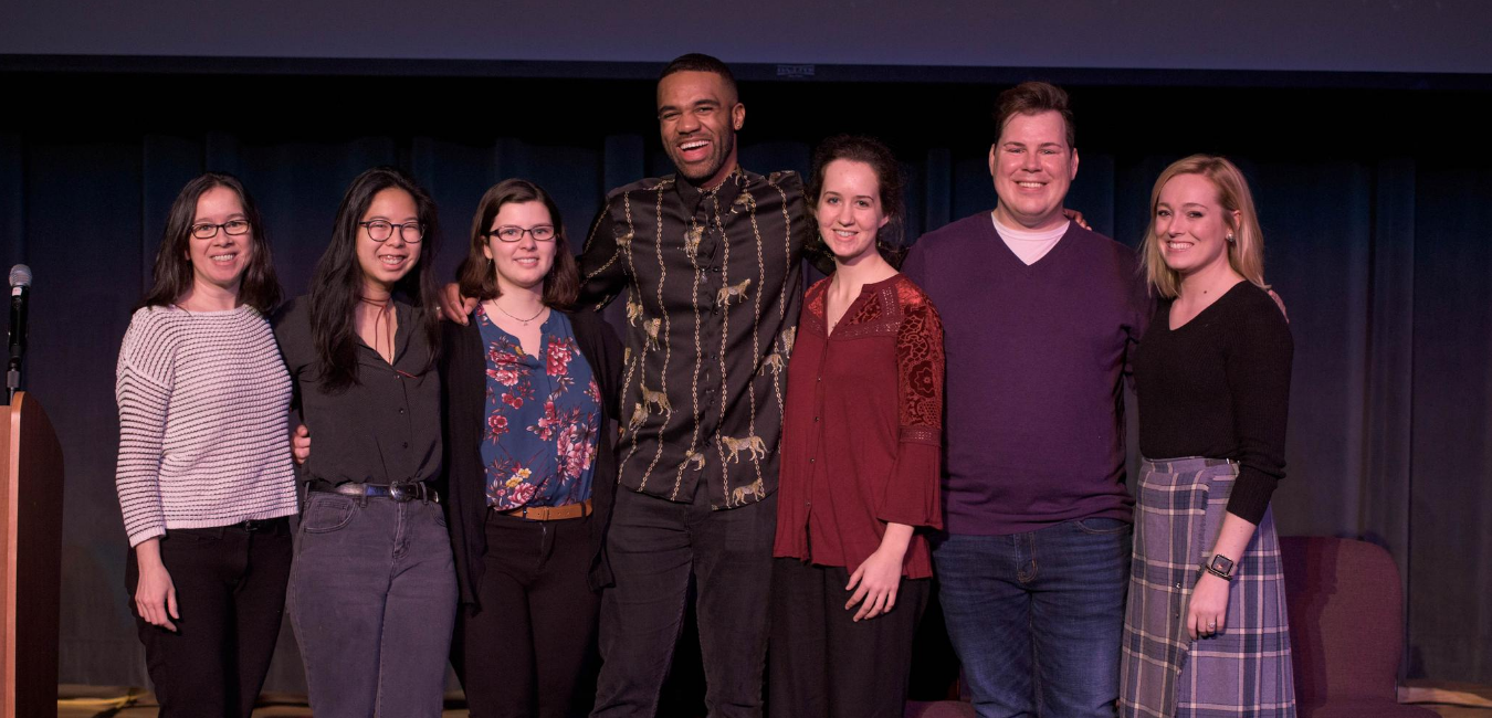 group of students on stage with guest speaker from the annual symposium 