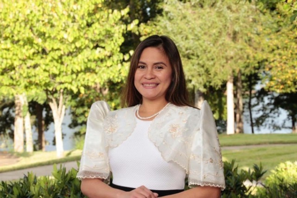 headshot of a student with trees behind her