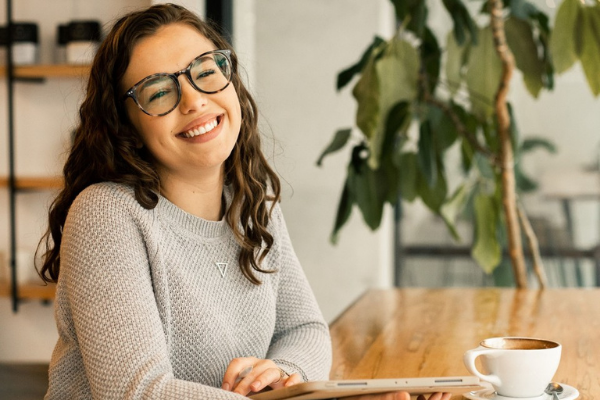 photo of recent graduate sitting at a coffee shop smiling