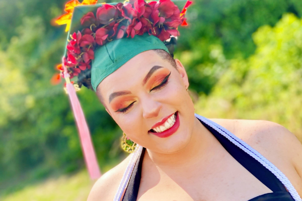 student with flowers on her grad cap smiling with her eyes closed outside