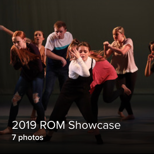 group of students dancing on stage, one female front and center with a dramatic look on her face, reaching her hand