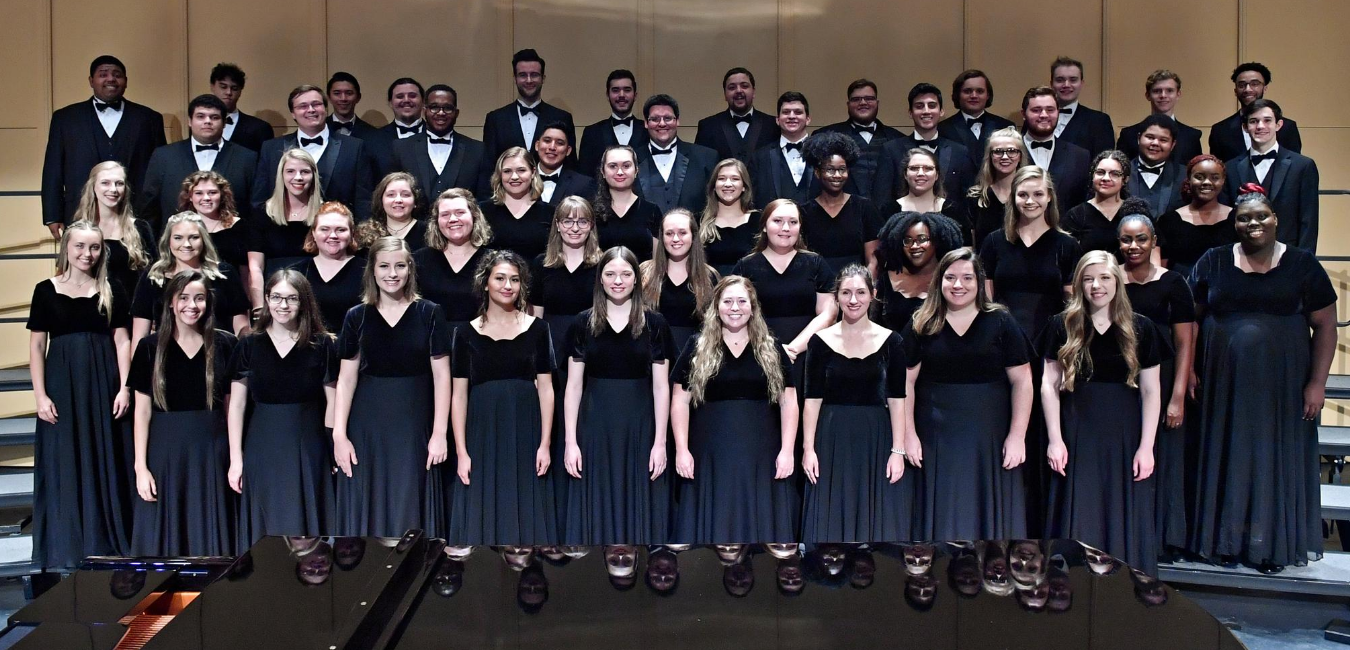 large group of music students in black formal wear standing on the bleachers