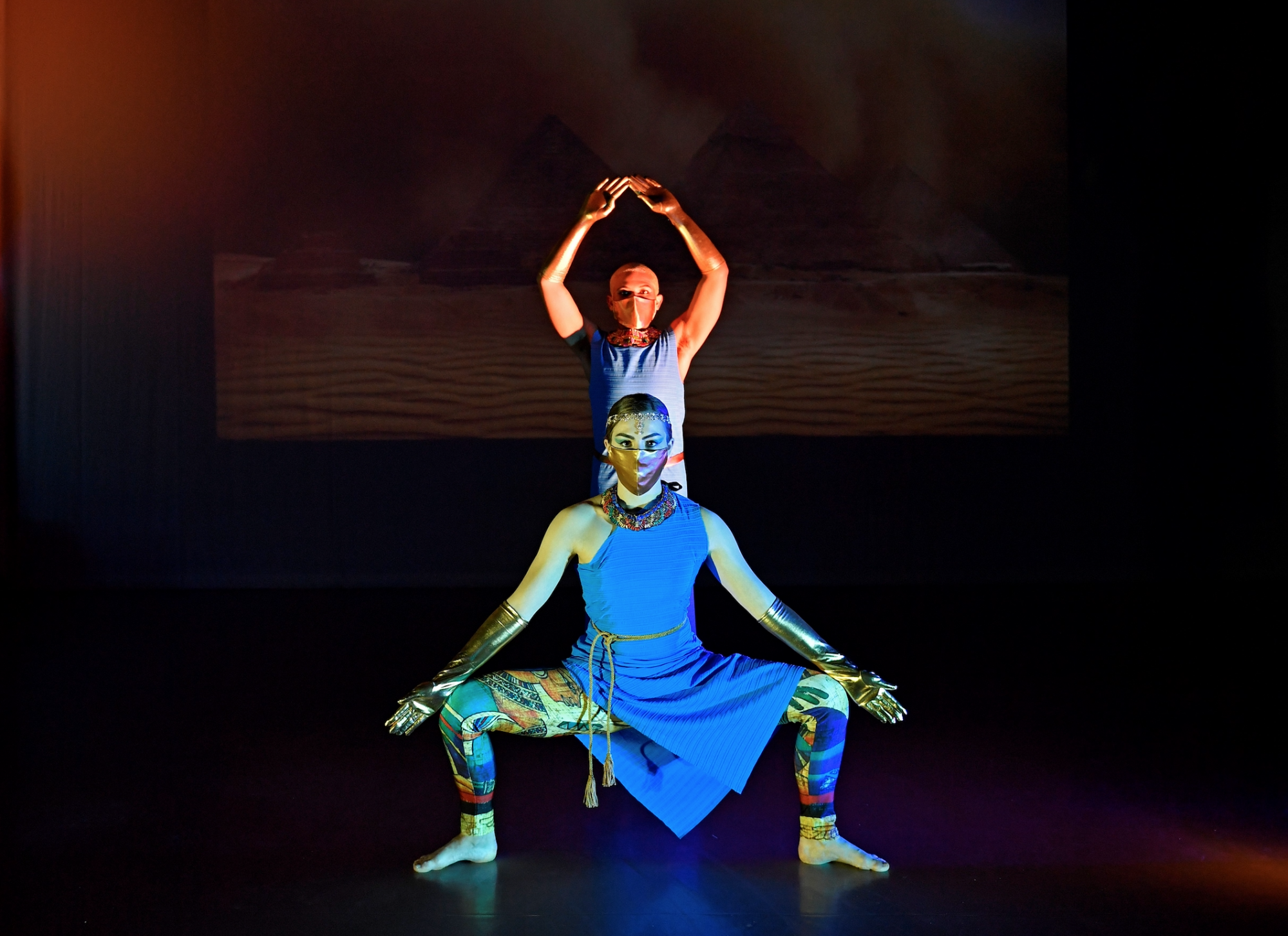 two dancers in masks and blue costumes on stage