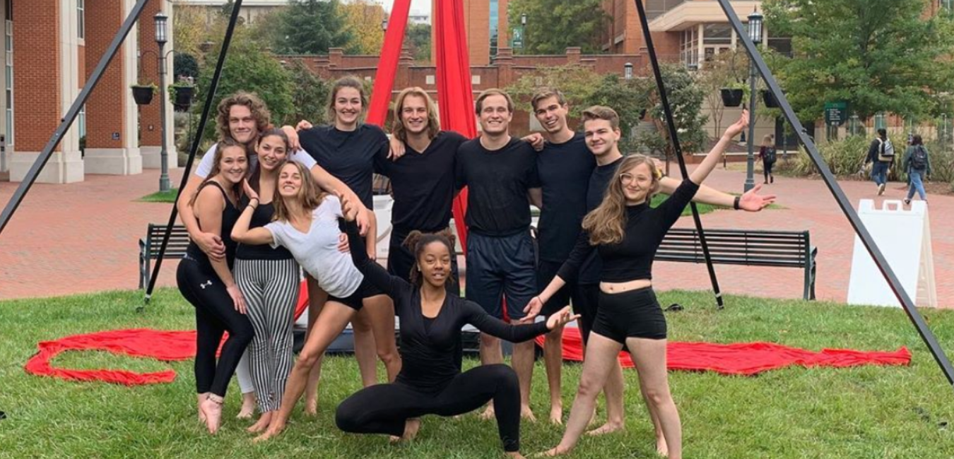 group of students after a circus performance with red ribbon behind them