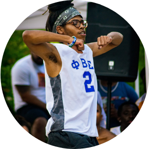 Black male theatre student in a fraternity jersey dancing on stage