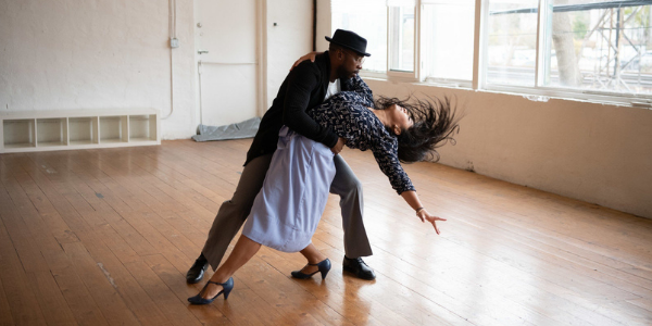 a beige studio with window with a man and woman dancing in a dip