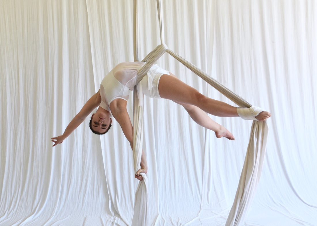 women on silks in all white hanging upside down in a backbend